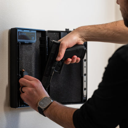 Wall-mounted Stopbox being used to secure a handgun, with a person placing the firearm inside the compartment.
