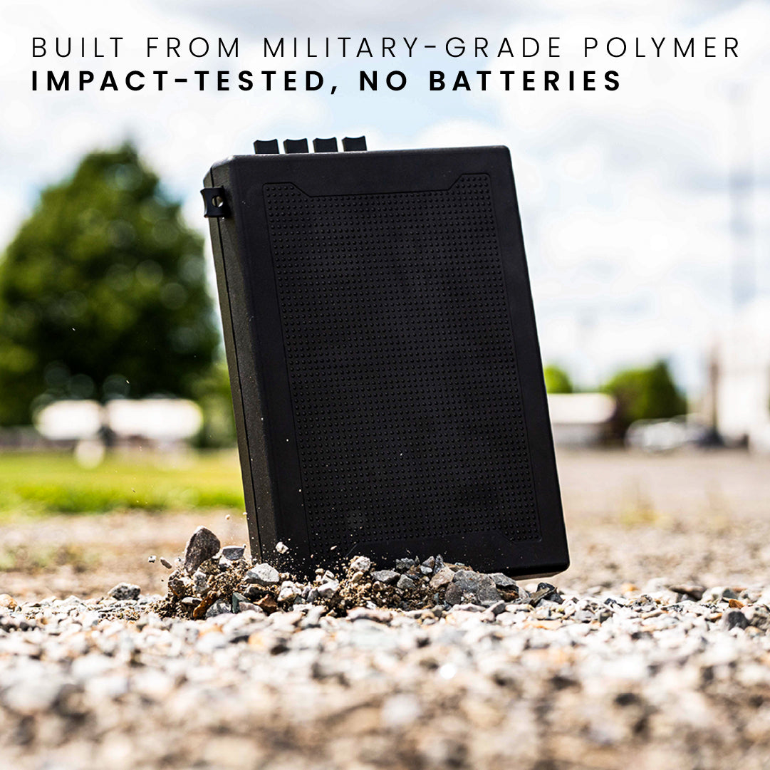 STOPBOX PRO in black, made from military-grade polymer, shown on gravel with a blurred background of trees and buildings.