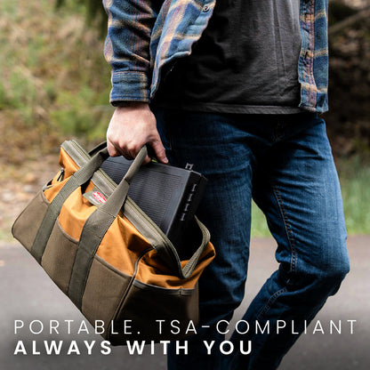 STOPBOX PRO in a tan and green bag, held by a person wearing a plaid shirt and jeans, outdoors on a path.